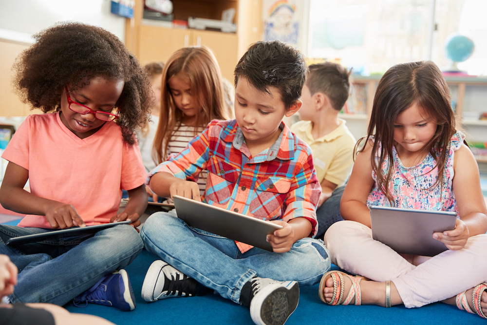 Kindergarten students learning on tablets